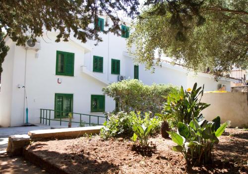 a white building with green shuttered windows and plants at Villa Mallandrino in Mondello