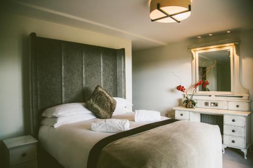 a bedroom with two beds and a dresser and a mirror at Galgorm in Ballymena