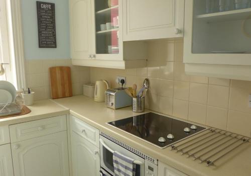 a kitchen with white cabinets and a sink at Beach View in North Berwick