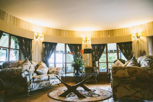 a living room with couches and a table and windows at Galgorm in Ballymena