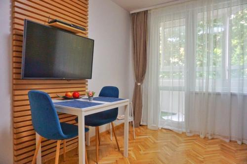 une table à manger avec des chaises bleues et une télévision à écran plat dans l'établissement White Central Apartment, à Varna