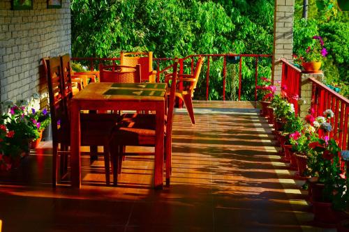a wooden table and chairs on a deck at Majkhali Woods, Ranikhet, By Himalayan Eco Lodges in Rānīkhet