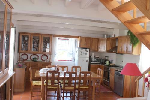 una cocina con armarios de madera, mesa y sillas en Casa da Aguada, en Lajes do Pico