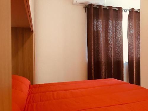 a bedroom with an orange bed and a window at CAV Mameli in Dorgali