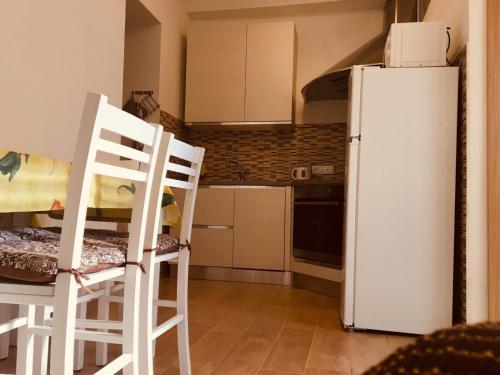 a kitchen with two white chairs and a refrigerator at CAV Mameli in Dorgali