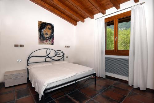 a bedroom with a bed and a painting on the wall at Les Maisons - Ruculì Hospitality in Tignale