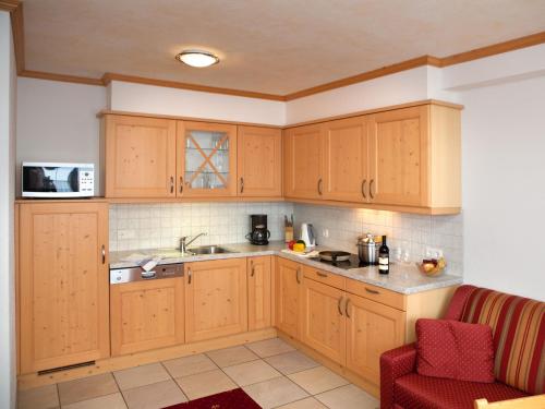 a kitchen with wooden cabinets and a red chair at Landhaus Gastein in Dorfgastein