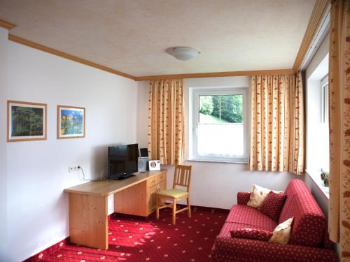 a room with a desk and a couch and a television at Landhaus Gastein in Dorfgastein