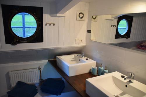 a bathroom with a white sink and two windows at Boathotel Rotterdam Anna in Rotterdam
