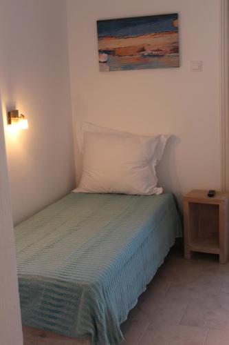 a bed with a pillow and a painting on the wall at Londos Hotel in Piso Livadi
