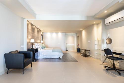 Cette chambre comprend un lit, un bureau et des chaises. dans l'établissement Rooms & Suites Loft 2E Deluxe Edition Arrecife, à Arrecife