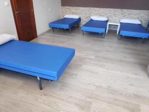 3 niebieskie łóżka w pokoju z drewnianą podłogą w obiekcie Albergue Mar de Rostro w mieście Fisterra