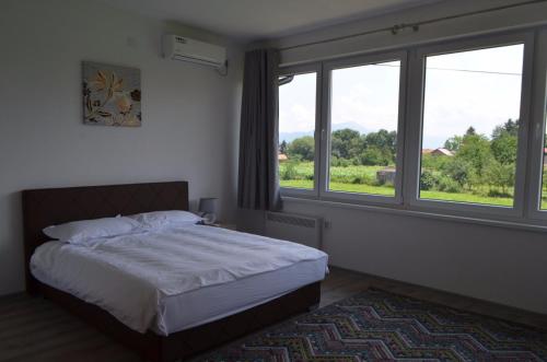a bedroom with a bed and two large windows at Dream Villa in Sarajevo