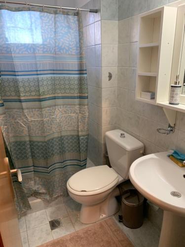 a bathroom with a toilet and a shower curtain at Sealake View in Mesolongion