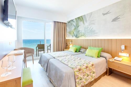 a hotel room with a bed and a view of the ocean at Universal Hotel Castell Royal in Canyamel