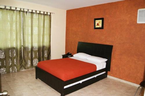 1 dormitorio con 1 cama con paredes de color naranja y ventana en Hotel Marvento II, en Salinas