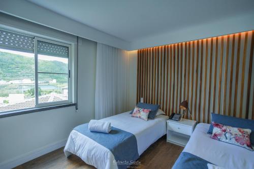 a bedroom with a bed and a chair and a window at Hotel Teresinha in Praia da Vitória
