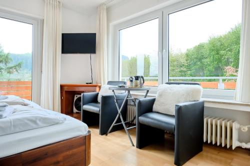 a bedroom with a bed and a table and chairs at Pension Haus am Einberg in Meschede