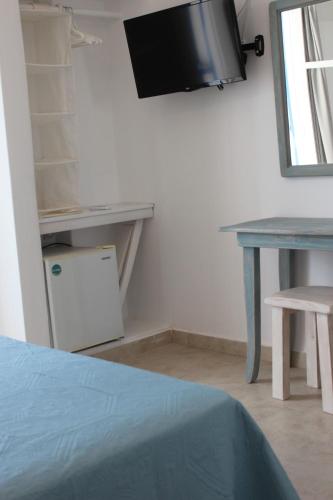 a room with a table and a tv on the wall at Londos Hotel in Piso Livadi