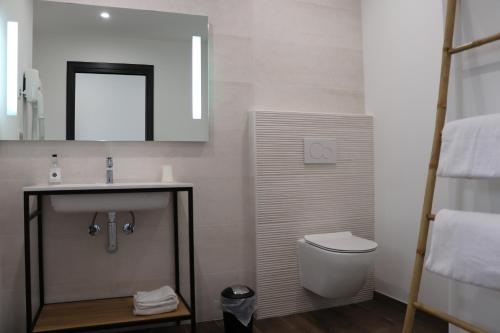 La salle de bains est pourvue d'un lavabo, de toilettes et d'un miroir. dans l'établissement Hotel Fazio, à Bonifacio