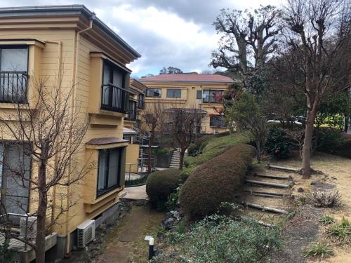a yellow building with trees and bushes next to a house at 伊道荘園 in Futo