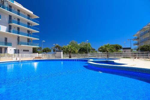 une grande piscine bleue à côté d'un immeuble dans l'établissement UHC Mar Augusta Family Complex, à Cambrils