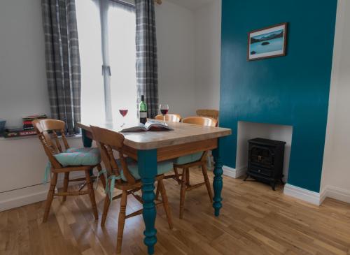a dining room with a table with chairs and a fireplace at Madoc Brook Cottage in Conwy