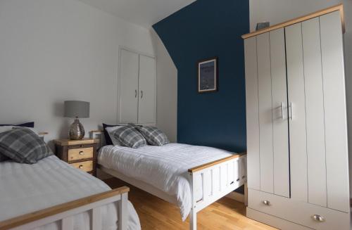 a bedroom with two beds and a blue wall at Madoc Brook Cottage in Conwy
