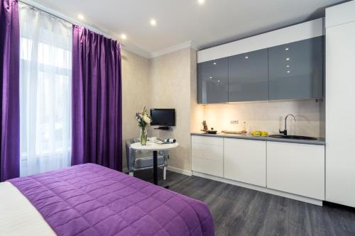 a bedroom with a purple bed and a kitchen at Apartments in City Center Area in Kyiv