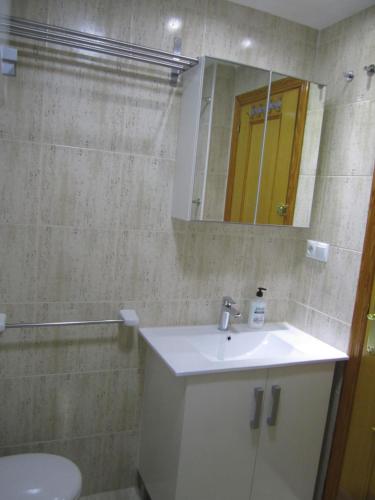 y baño con lavabo, espejo y aseo. en Holiday Apartment 5 min to Levante beach en Benidorm