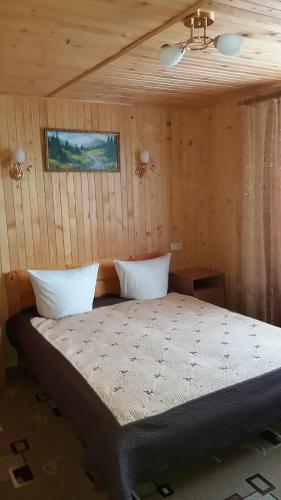 a bed in a room with a wooden wall at raduga karpat in Yaremche