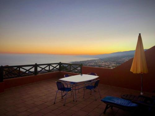 eine Terrasse mit einem Tisch, Stühlen und einem Sonnenschirm in der Unterkunft Casa Ida in Garachico
