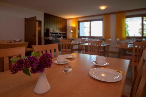 a dining room with a table with a vase of flowers on it at Seehotel Weissensee in Füssen