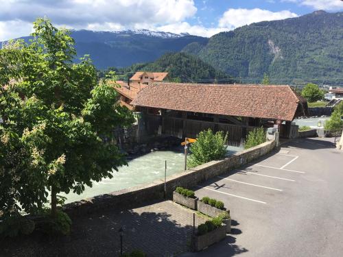 a building with a river in front of a mountain at Historic Hotel Steinbock in Wilderswil