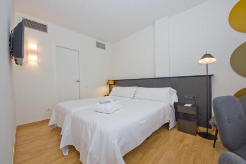 a bedroom with a white bed and a chair at Aparthotel Atenea Valles in Granollers