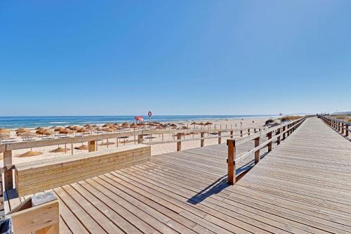 a wooden boardwalk leading to the beach with umbrellas at Monte Gordo Beach 1 by Homing in Monte Gordo