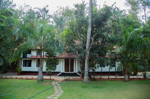 a house with a hose in a yard with palm trees at Orchid Trails Resort in Sultan Bathery