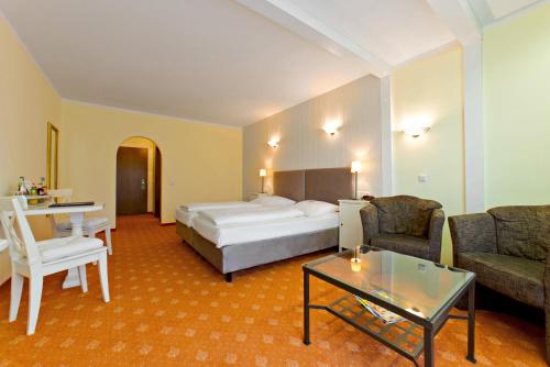 a hotel room with a bed and a couch and a table at Hotel Räucherhansl in Loiching