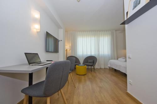 a room with a desk with chairs and a laptop at Aparthotel Atenea Valles in Granollers