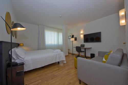 a hotel room with a bed and a couch at Aparthotel Atenea Valles in Granollers