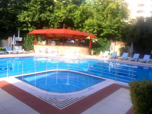 a large swimming pool with a red umbrella and chairs at Gold Sun 4 in Mahmutlar