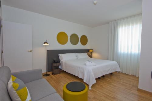 a hotel room with a bed, chair, lamp and a window at Aparthotel Atenea Valles in Granollers