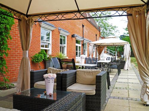 an outdoor patio with wicker chairs and an umbrella at The Pinewood Hotel in Slough
