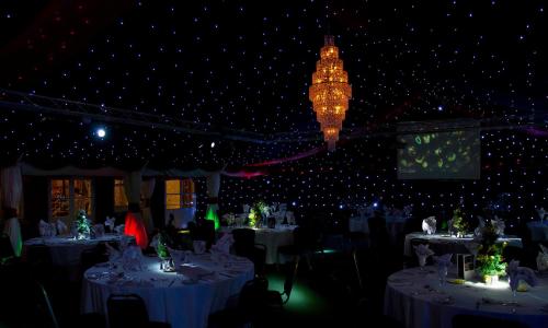 a dining room with white tables and a chandelier at The Pinewood Hotel in Slough