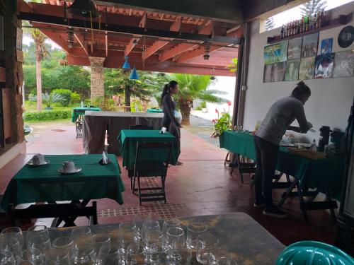 2 personnes debout dans un restaurant avec des tables vertes dans l'établissement Pousada Sao Lourenco, à Ubajara