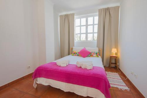 a bedroom with a large bed with pink blanket at SUNNY HOUSE by Stay in Alentejo in Vila Nova de Milfontes