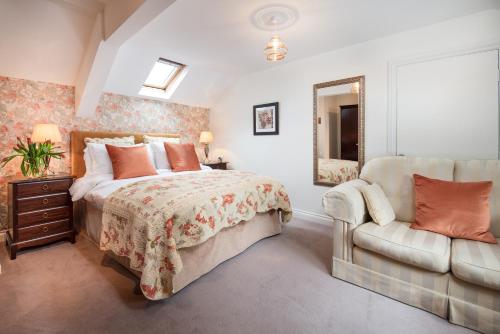 een slaapkamer met een bed, een bank en een spiegel bij Coach House B & B in Alnwick