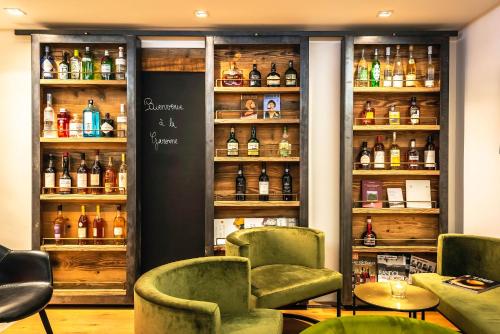 a bar with green chairs and bottles of alcohol at Hôtel La Garenne in Saverne