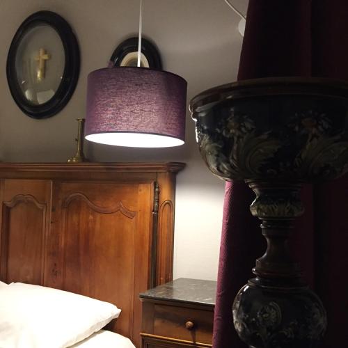 a lamp in a bedroom with a bed and a table at Hotel Auberge des Remparts in Laval