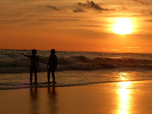 two people standing on the beach watching the sunset at Mundo Milo Eco Lodge in Playa Junquillal